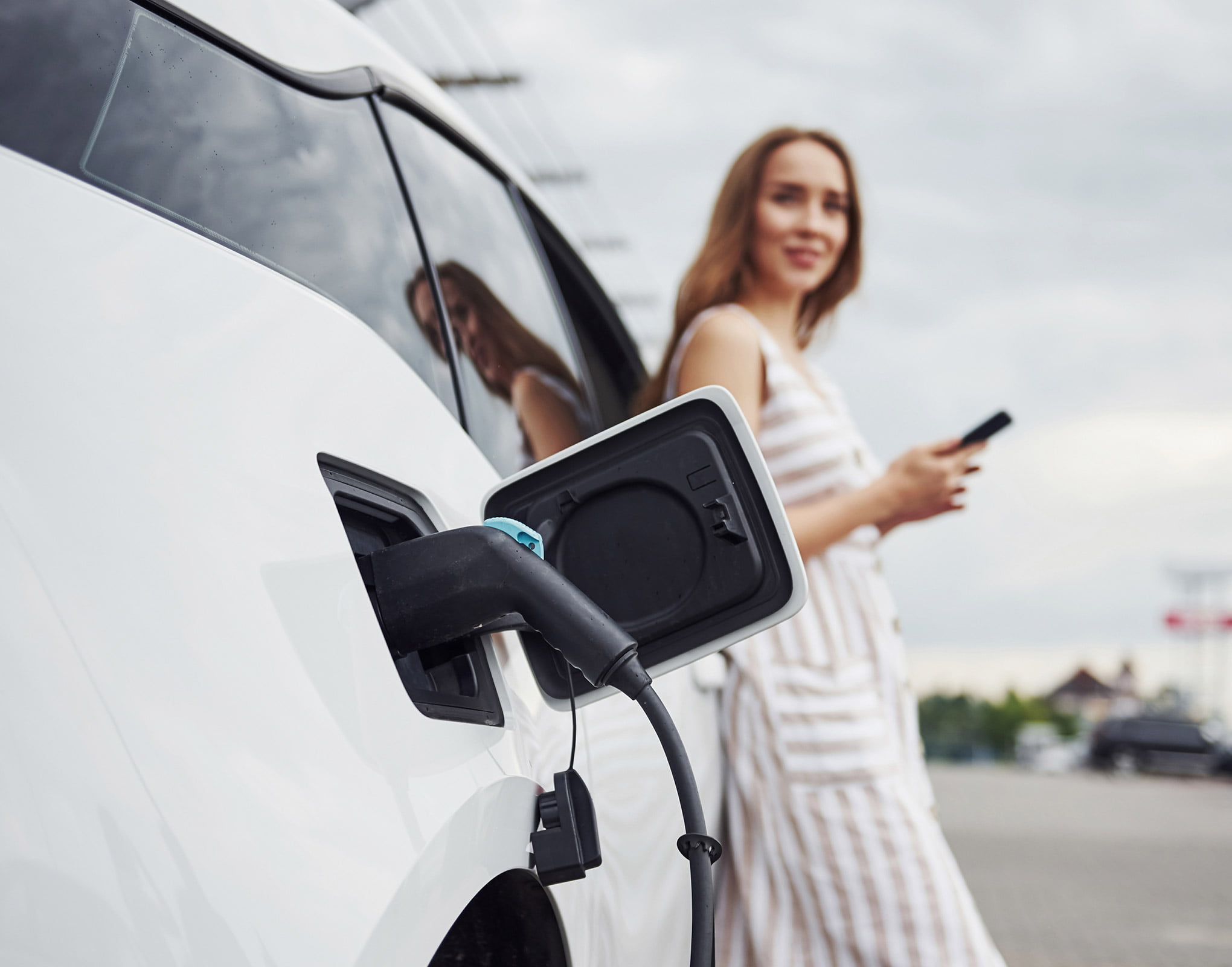 Women Stood by Electrical Car Charging Station