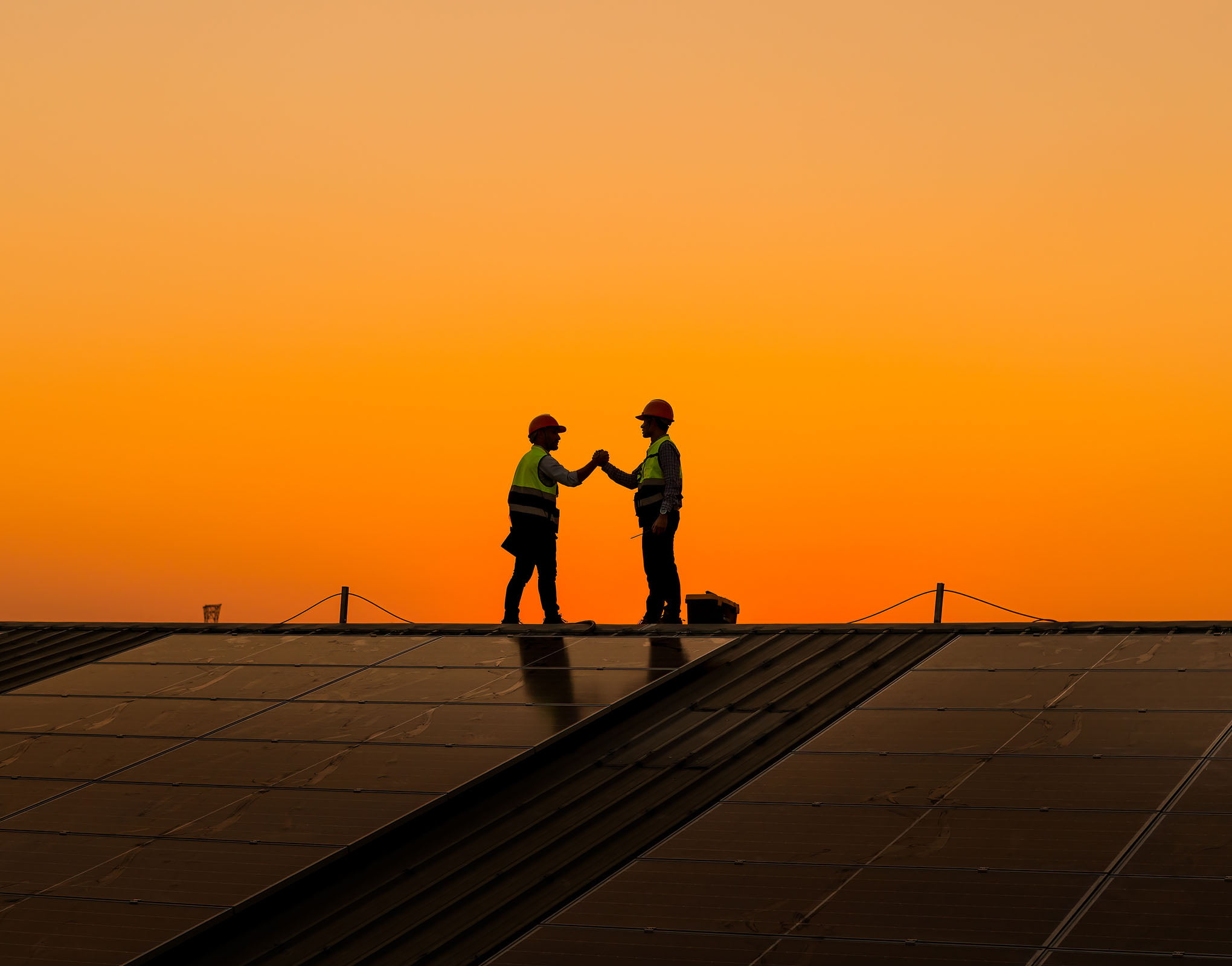 Two LCM Employees Shaking Hands With The Sun Setting