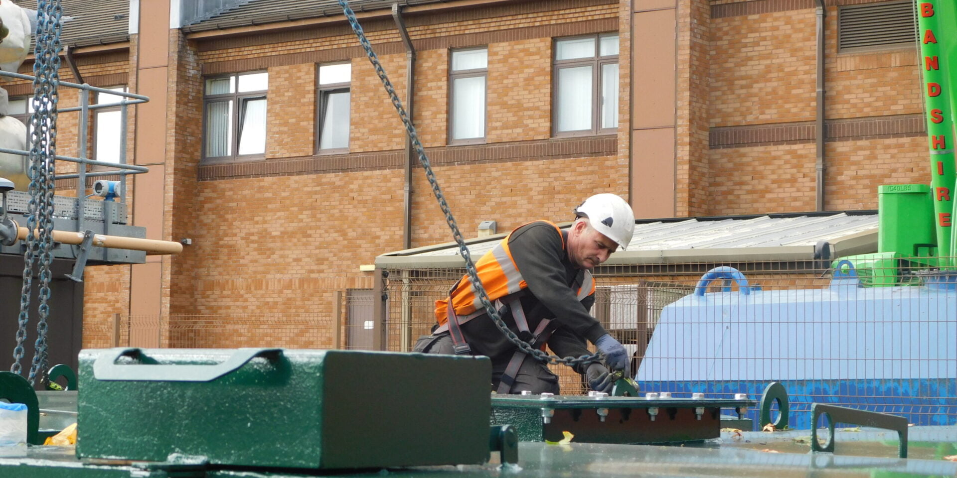 LCM working attaching chain to container lid.